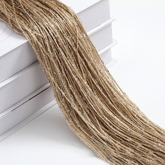 Champagne string curtain with flashing silver metallic threads, draped over white boxes. - Image 6
