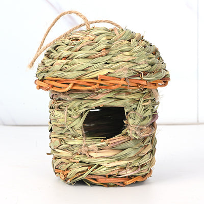 Hand-woven straw bird's nest with a round entrance, made from green and brown grass, hanging from a tree branch. - Image 8