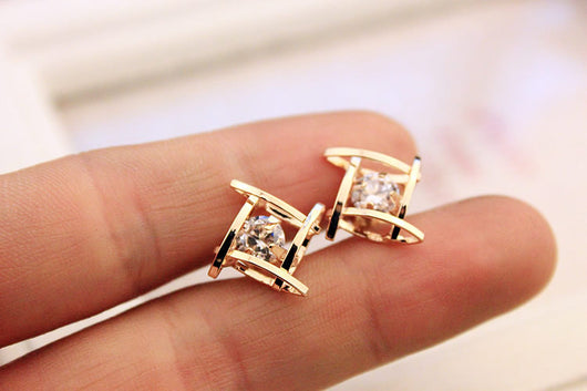 Gold-tone square stud earrings with clear zircon gemstones set in a hollow tic-tac-toe geometric frame. - Image 6