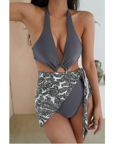 Woman in a dark grey one-piece swimsuit with a deep V-neck, halter straps, and side cut-outs with a gold O-ring. - Image 7