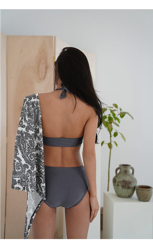 Woman in a dark grey one-piece swimsuit with a deep V-neck, halter straps, and side cut-outs with a gold O-ring. - Image 5