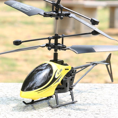 Yellow and black remote control helicopter toy with dual rotors and landing gear, resting on a light outdoor surface. - Image 5