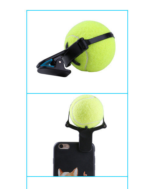 Black pet selfie artifact phone clip with blue accents, holding a bright neon yellow tennis ball, shown attached to a smartphone. - Image 2