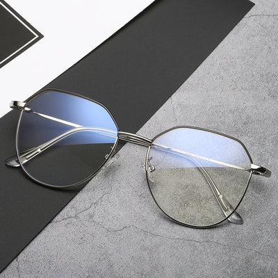 Black metal-framed glasses with irregular polygonal shape and anti-blue light lenses on a two-tone gray and black surface. - Image 4