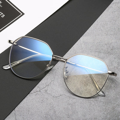 Black metal-framed glasses with irregular polygonal shape and anti-blue light lenses on a two-tone gray and black surface. - Image 3