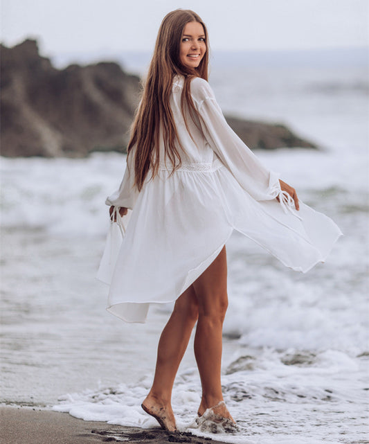 Woman in a sheer white long-sleeve beach cover-up with lace trim over an orange bikini top, standing by the ocean. - Image 2