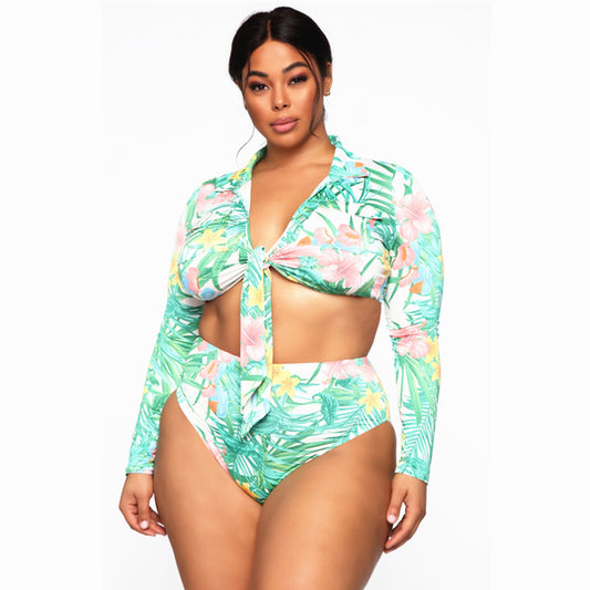 Plus size woman in a tropical print long-sleeve, tie-front crop top and high-waisted bikini bottoms.