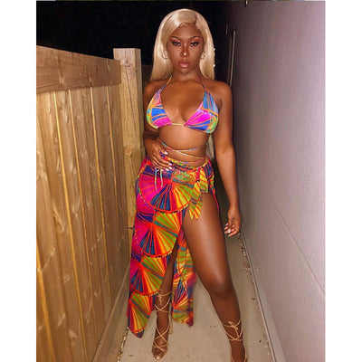 Woman wearing a vibrant multi-color abstract print three-piece bikini set with a matching sheer sarong on a balcony. - Image 11
