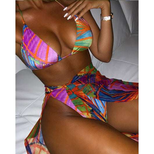 Woman wearing a vibrant multi-color abstract print three-piece bikini set with a matching sheer sarong on a balcony. - Image 12