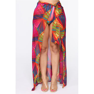 Woman wearing a vibrant multi-color abstract print three-piece bikini set with a matching sheer sarong on a balcony. - Image 4