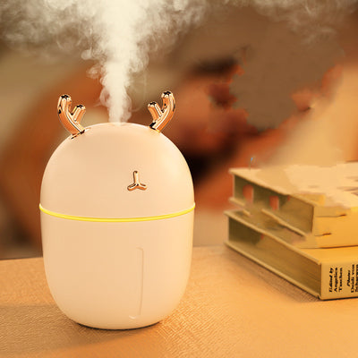 Pink egg-shaped humidifier with gold deer antlers, a deer head logo, and a glowing purple light band.
