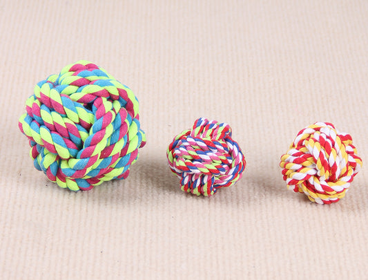 Three colorful knotted cotton rope ball dog toys in various sizes on a light beige surface.