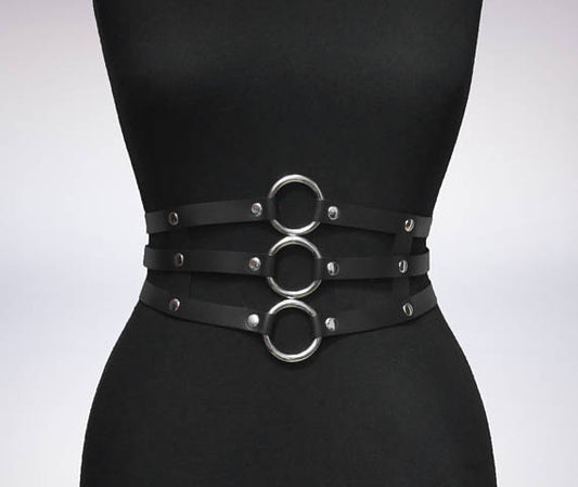 Women's black leather waist belt with three layers, silver-tone metal O-rings, and rivets on a black mannequin.