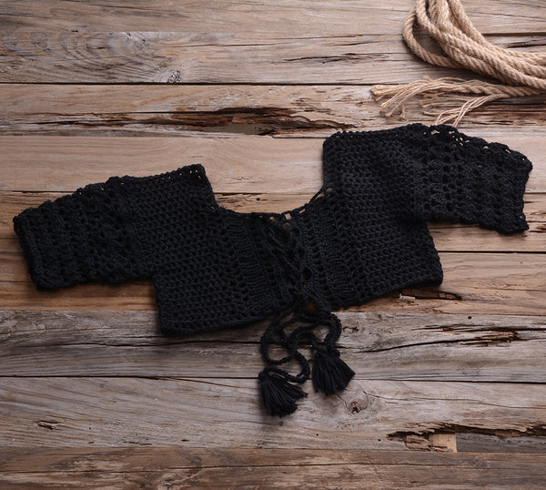Black crocheted off-the-shoulder crop top with short sleeves and a lace-up front featuring tassels.