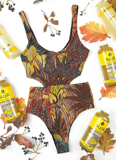 One-piece swimsuit with a vibrant tropical leaf print in yellow, brown, and blue, featuring stylish side cut-outs.