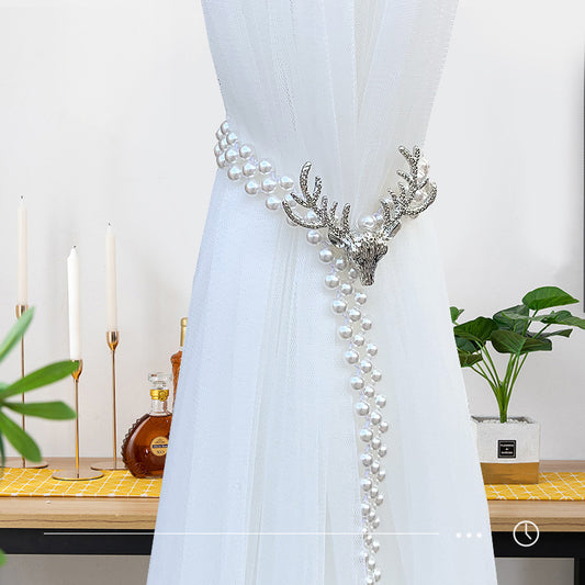 Silver elk head curtain tie-back with faux pearl strands holding back a sheer white curtain. - Image 2