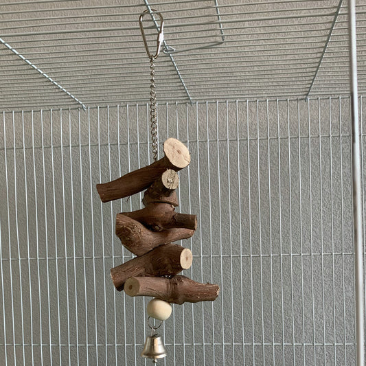Natural wood parrot vine molar string with a bell, hanging inside a wire bird cage for chewing and play.