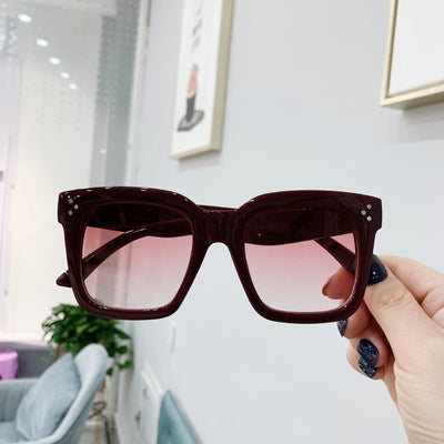 Retro oversized square sunglasses with a dark red frame and pink gradient lenses, held by a hand. - Image 4