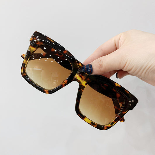 Retro oversized square sunglasses with a dark red frame and pink gradient lenses, held by a hand. - Image 2