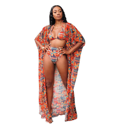 Woman wearing a red, orange, and blue geometric print three-piece swimsuit with a high-waisted bikini and long kimono cover-up. - Image 3