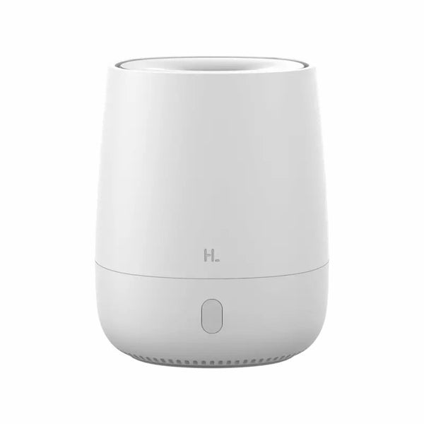 White minimalist aroma diffuser emitting mist, with a single button, on a white nightstand next to a bed.