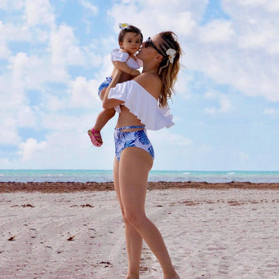 Family matching swimsuits with white and blue tropical leaf print, including men's shorts, women's and girl's ruffled one-shoulder bikinis. - Image 8