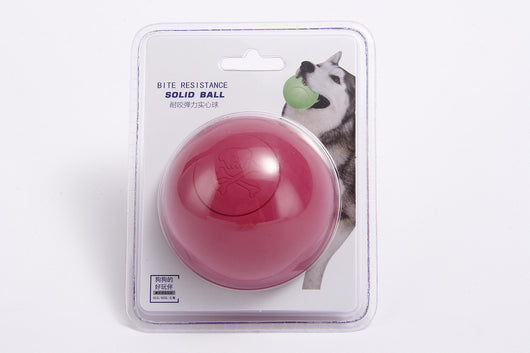 Pink rubber pet bouncy ball with an embossed skull and crossbones design, held in a hand. - Image 12