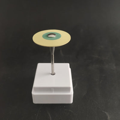 Zirconia diamond grinding head with a red and green abrasive disc on a metal shank, displayed in a white holder.