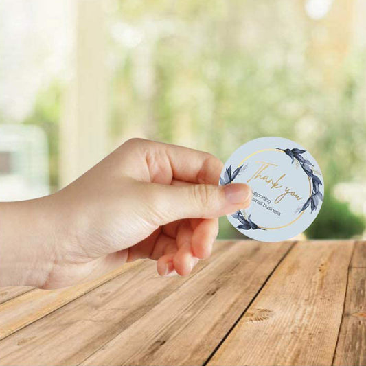 Roll of round 'Thank You for supporting my small business' stickers with a blue floral wreath design. - Image 2