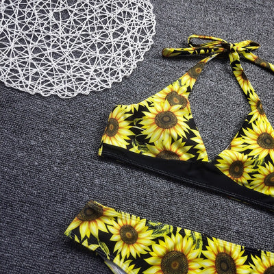 Women's two-piece bikini with a vibrant sunflower print on a black background, featuring a halter-neck top and matching bottom. - Image 2