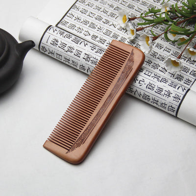 Light brown wooden comb with fine teeth and an ergonomic handle featuring engraved traditional Chinese patterns and a stylized face. - Image 3