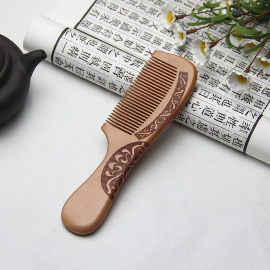Light brown wooden comb with fine teeth and an ergonomic handle featuring engraved traditional Chinese patterns and a stylized face. - Image 5