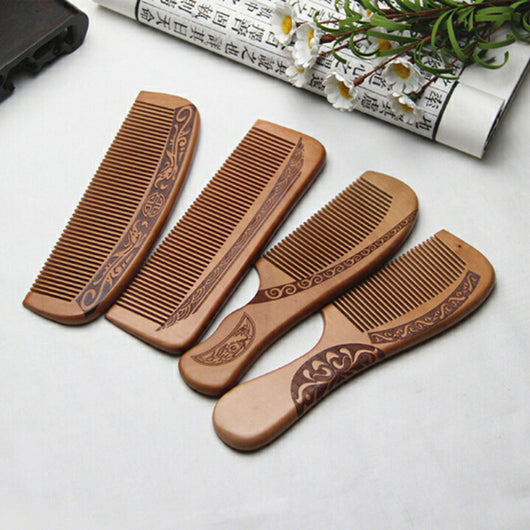 Light brown wooden comb with fine teeth and an ergonomic handle featuring engraved traditional Chinese patterns and a stylized face.