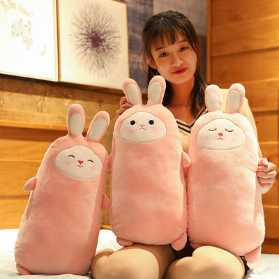 Pink rabbit plush doll with closed eyes, soft and elongated, standing on a bed. - Image 2