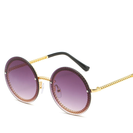 Frameless round sunglasses with pink gradient lenses and gold-tone chain detail on temples and lens edges.