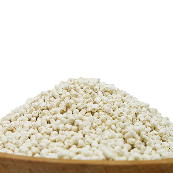 Close-up of a pile of light-colored, irregularly shaped tofu cat litter pellets in a wooden bowl.
