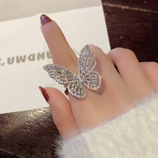 Sparkling silver-tone butterfly ring with clear baguette and round cut stones on a white surface. - Image 5
