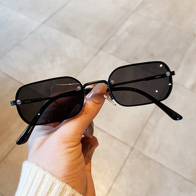 Trendy small frame square sunglasses with brown gradient lenses and gold-tone metal frames, held by a hand.