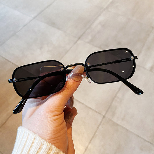 Trendy small frame square sunglasses with brown gradient lenses and gold-tone metal frames, held by a hand.