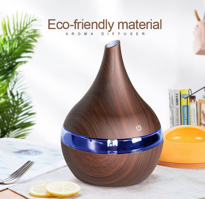 Light wood grain teardrop-shaped mini humidifier and aroma diffuser with a clear water tank and power button.
