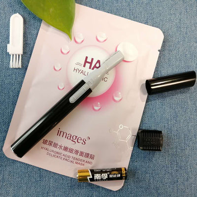 Pink electric shaver with cap off, showing blade, comb attachment, cleaning brush, and AA battery on a pink sheet mask. - Image 4
