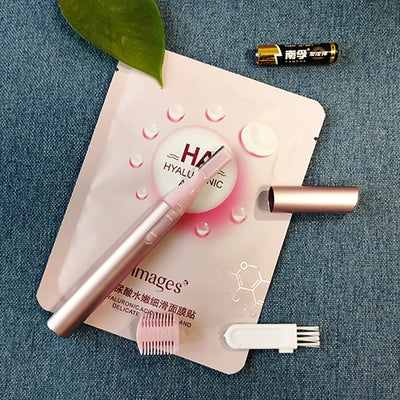 Pink electric shaver with cap off, showing blade, comb attachment, cleaning brush, and AA battery on a pink sheet mask. - Image 3