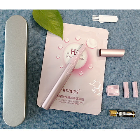 Pink electric shaver with cap off, showing blade, comb attachment, cleaning brush, and AA battery on a pink sheet mask. - Image 7