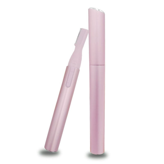 Pink electric shaver with cap off, showing blade, comb attachment, cleaning brush, and AA battery on a pink sheet mask.