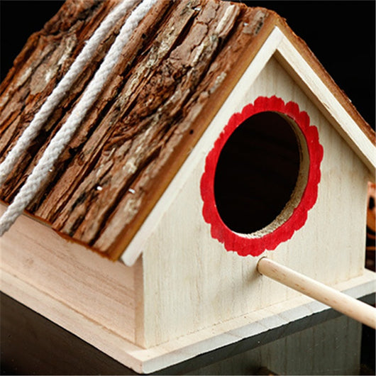 Rustic wooden birdhouse with bark roof, red scalloped entrance, and a hanging rope on a white background. - Image 2
