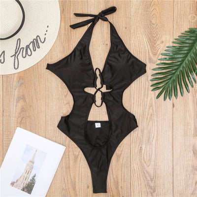 Woman wearing a black one-piece swimsuit with a halter neck, criss-cross front, and torso cut-outs, lying on a bed. - Image 13