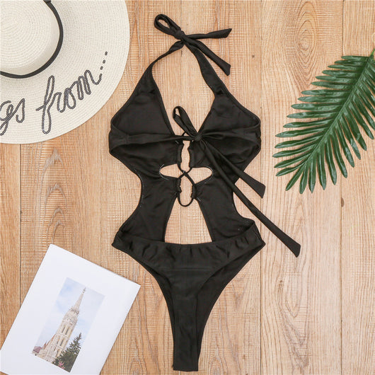 Woman wearing a black one-piece swimsuit with a halter neck, criss-cross front, and torso cut-outs, lying on a bed. - Image 14