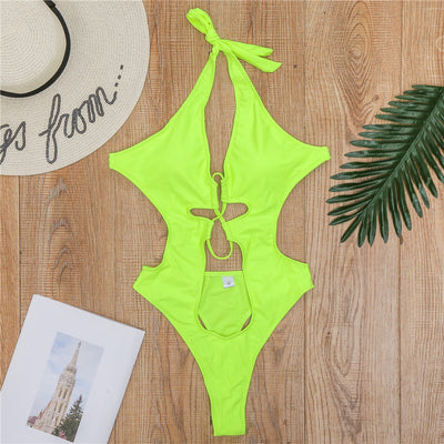 Woman wearing a black one-piece swimsuit with a halter neck, criss-cross front, and torso cut-outs, lying on a bed. - Image 15