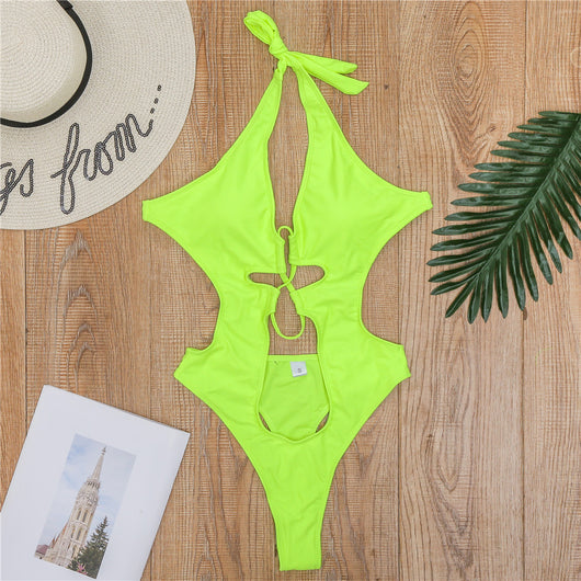 Woman wearing a black one-piece swimsuit with a halter neck, criss-cross front, and torso cut-outs, lying on a bed. - Image 15