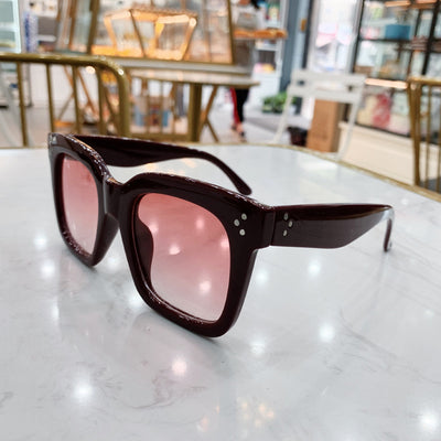 Retro oversized square sunglasses with a dark red frame and pink gradient lenses, held by a hand. - Image 12